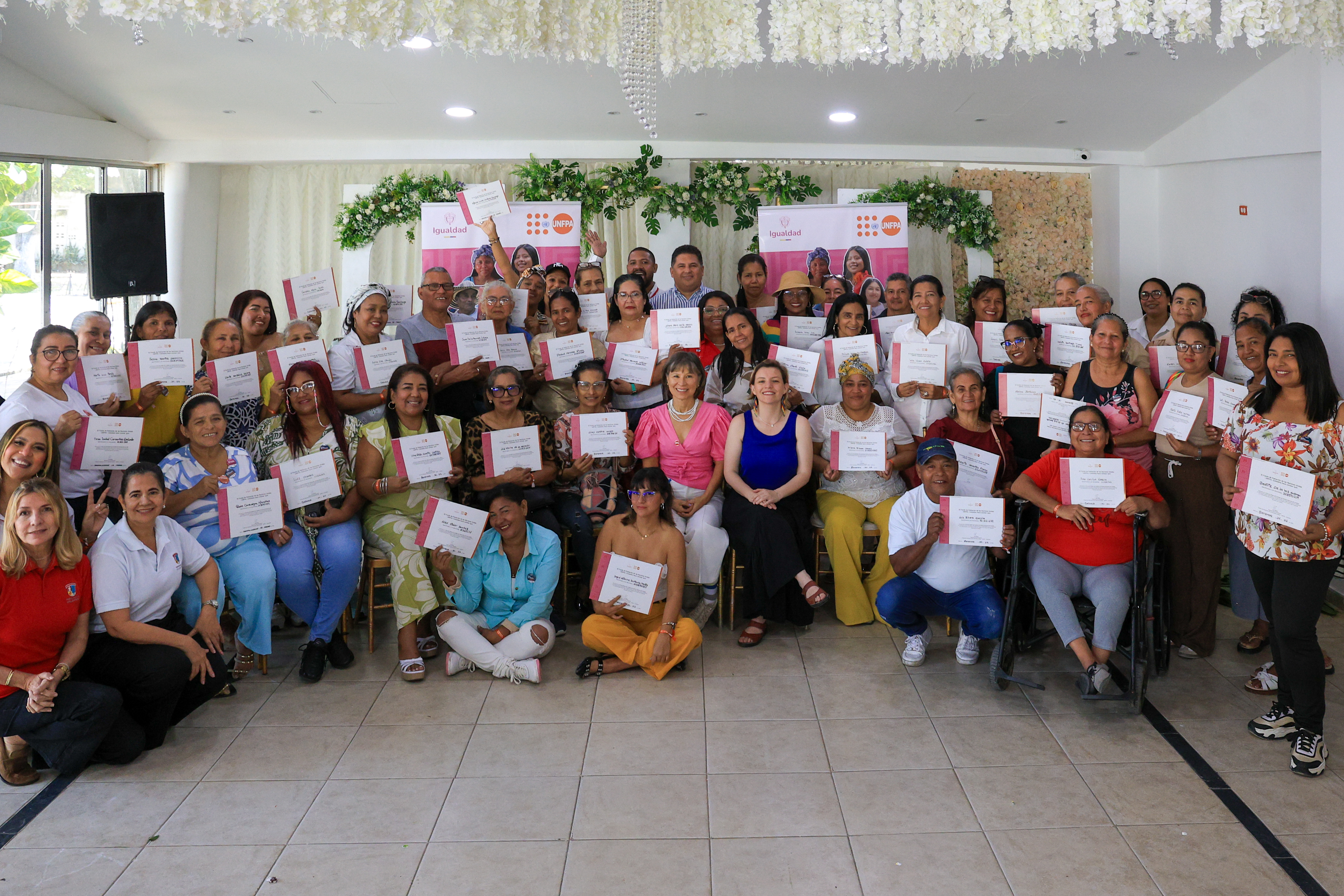 Grupo de personas cuiudadoras posan de pie y sentadas en el piso sosteniendo en sus manos el dilploma que las acredita su participación los talleres de formación política del Cuidado
