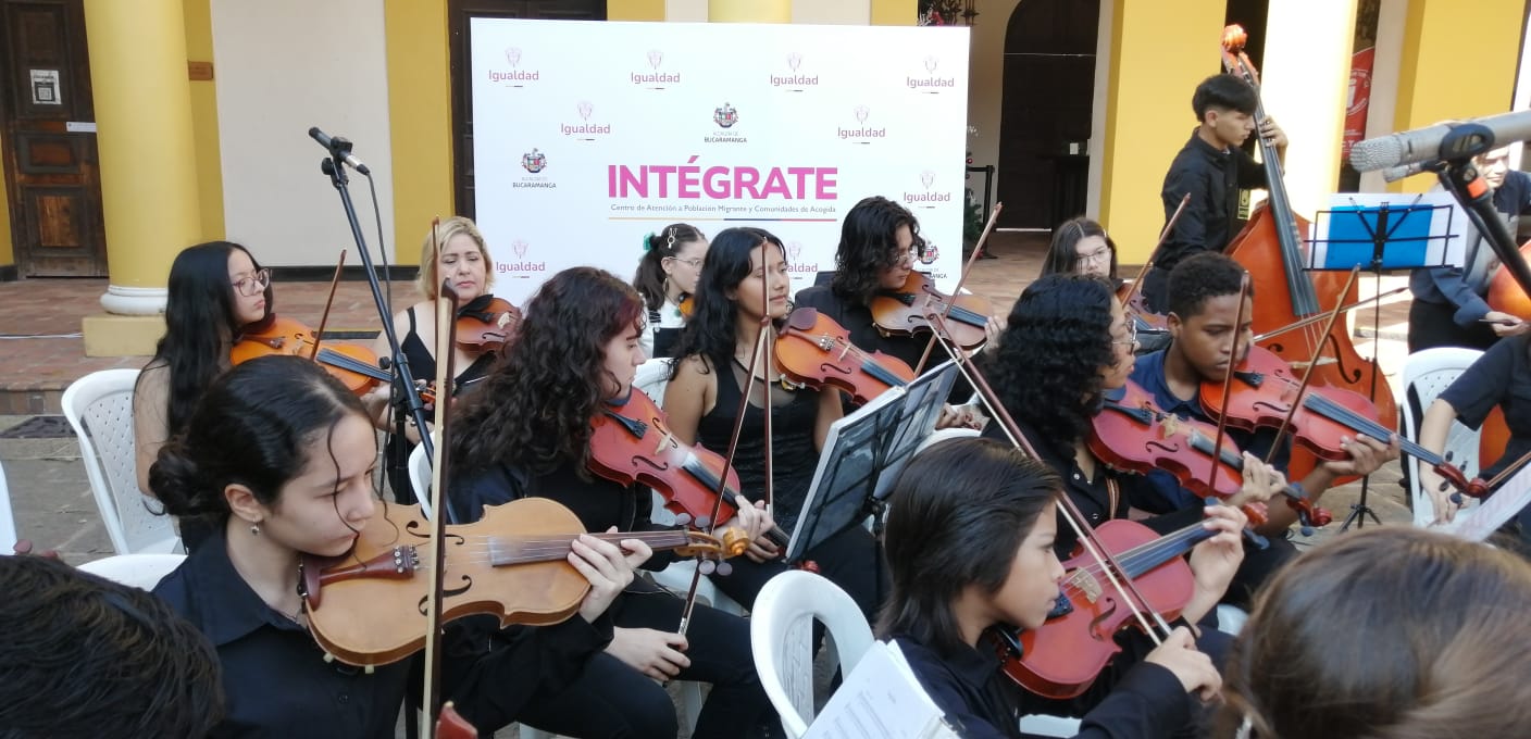 Grupo de jóvenes de la orquesta filarmónica de Bucaramanga con backing donde se lee la palabra Intégrate y el escudo del Ministerio de Igualdad y Equidad