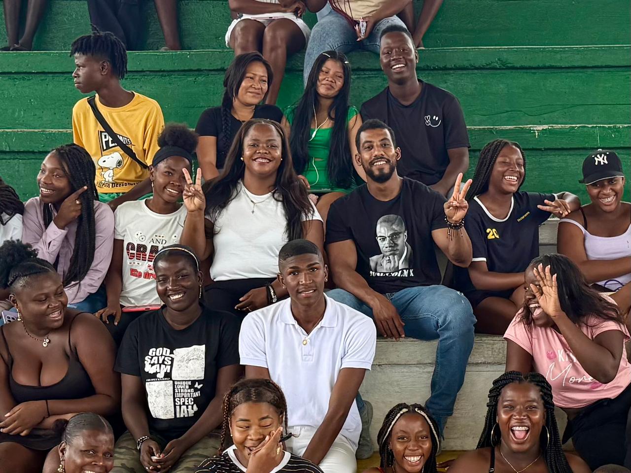 Jóvenes afro de Chocó posan alegres y sonrientes en la graderías de un coliseo durante una actividad de Jóvenes en Paz