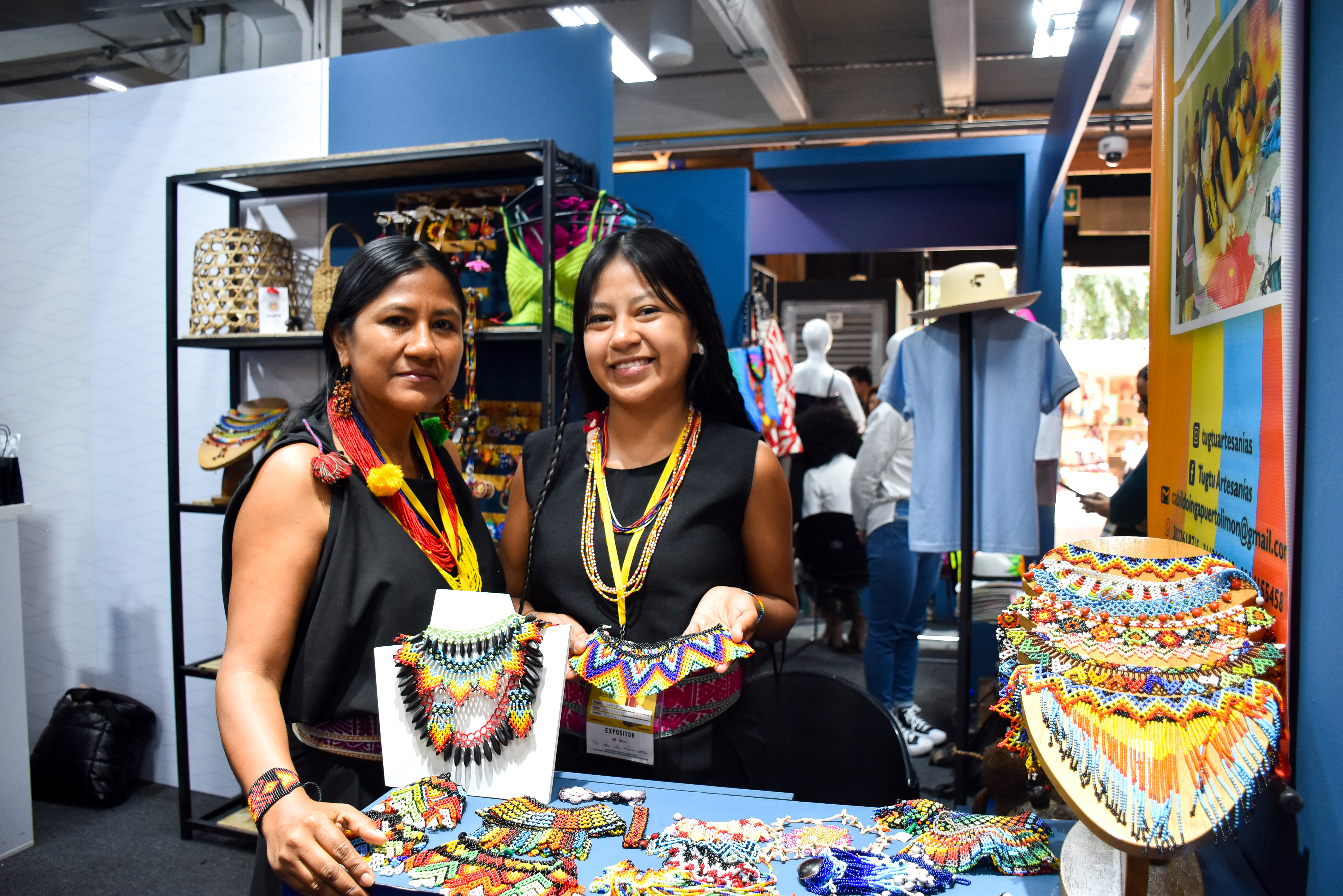 Dos mujeres nariñenses exhiben en una feria artesanal collares, pecheras, pulseras y otras artesanías propias de su cultura.