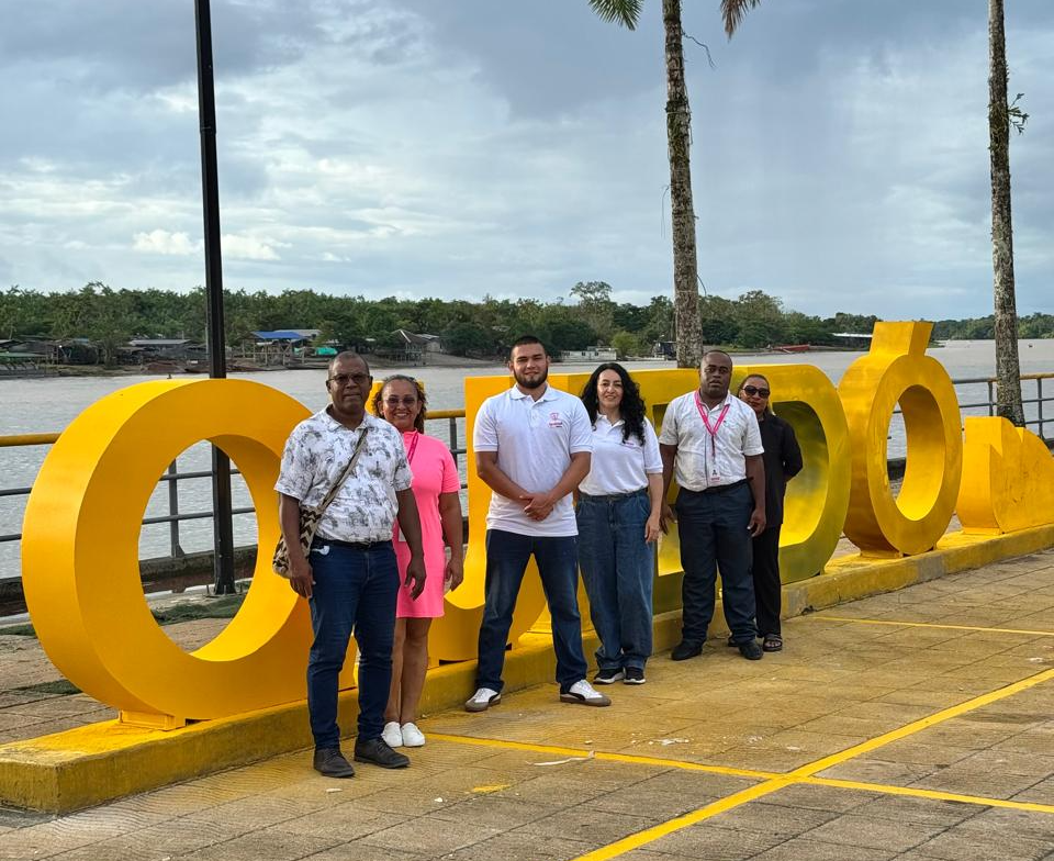 Funcionarios de Minigualdad posan de pie junto a letrero turístico gigante de Quibdó en la calle