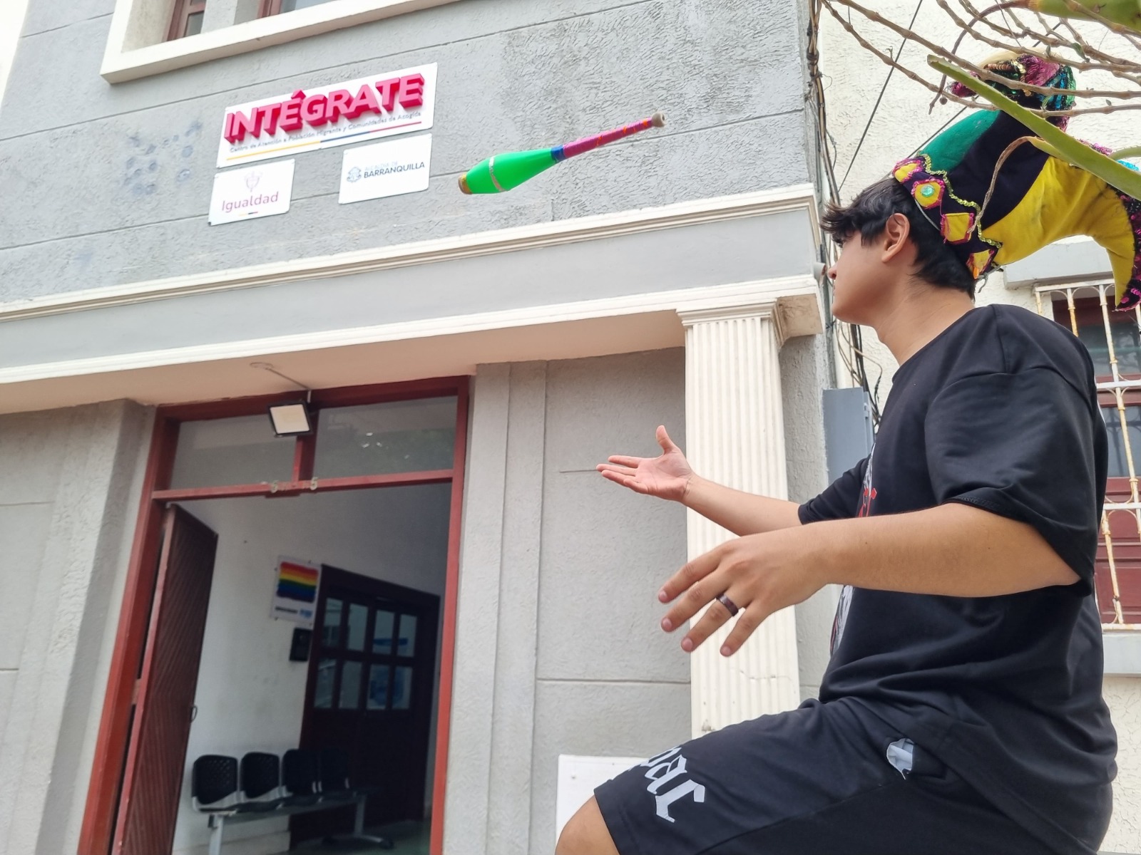 Malabarista joven practicva su arte  en calle de Barranquilla, de fondo se aprecia la fachada del Centro INTÉGRATE con sus puertas abiertas al público
