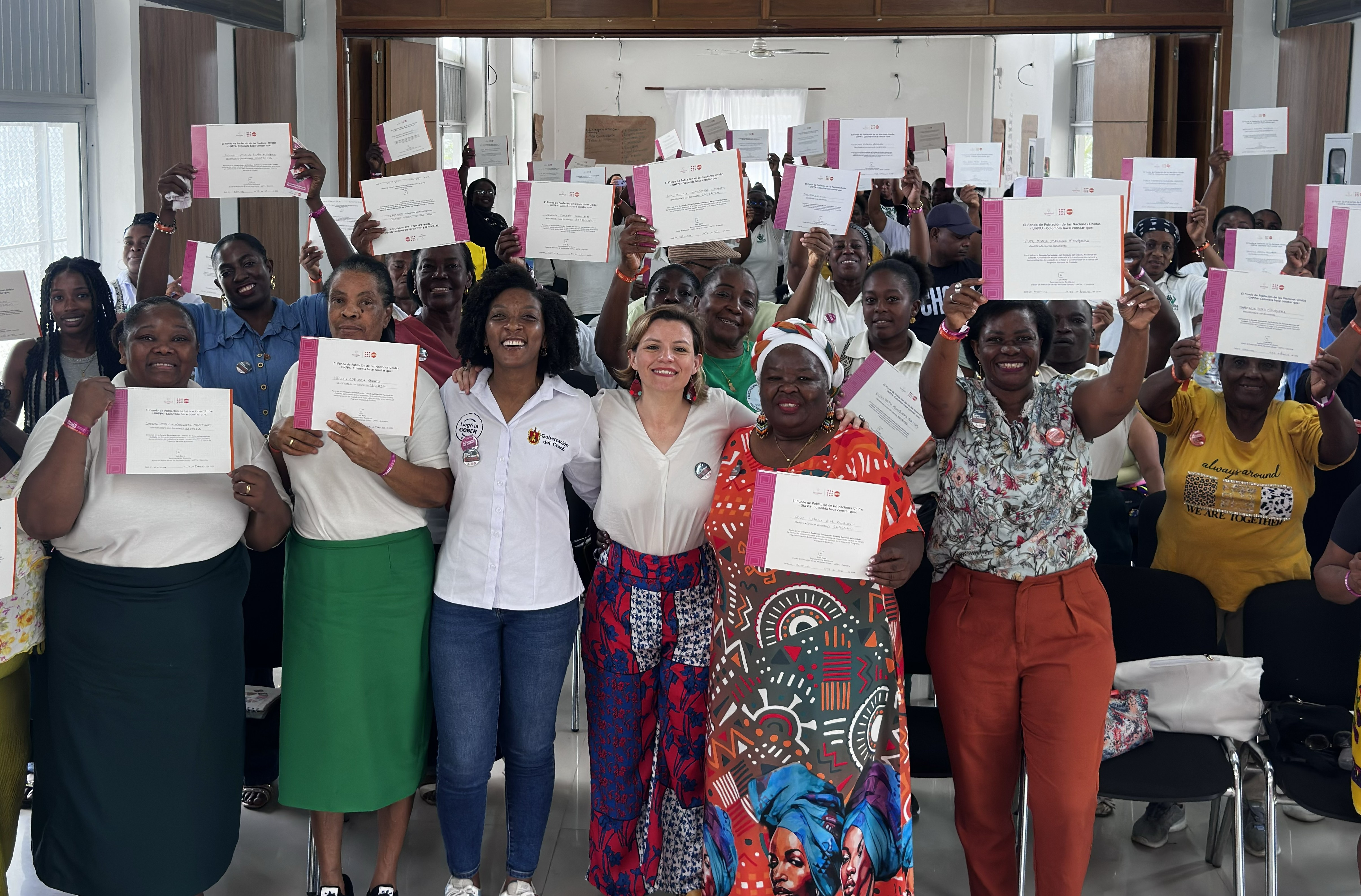 Mujeres cuidadoras sonriendo junto con la directora Natalia de Cuidado con sus respectivos diplomas de graduación