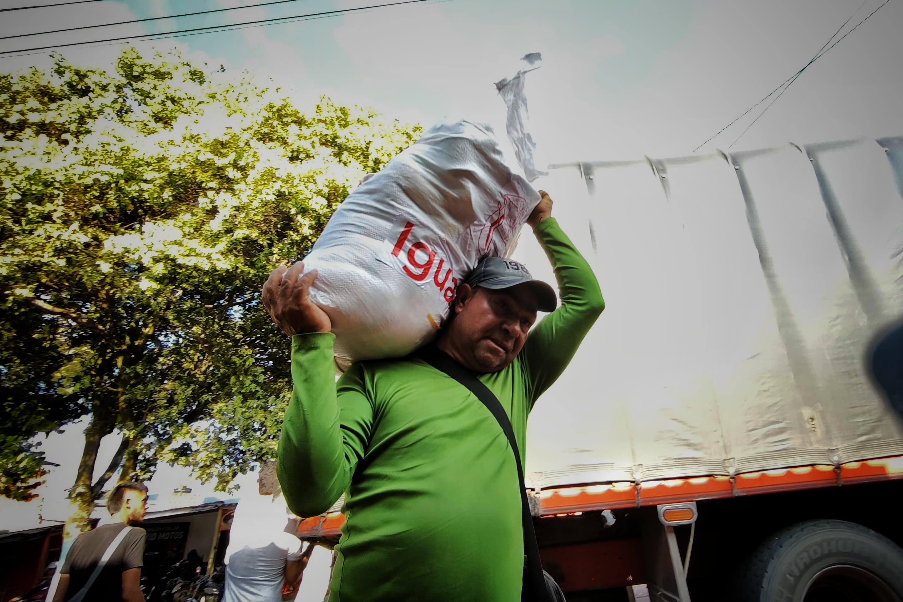 Hombre adulto con cachucha lleva al hombro bulto de comida entregada por el programa Hambre Cero