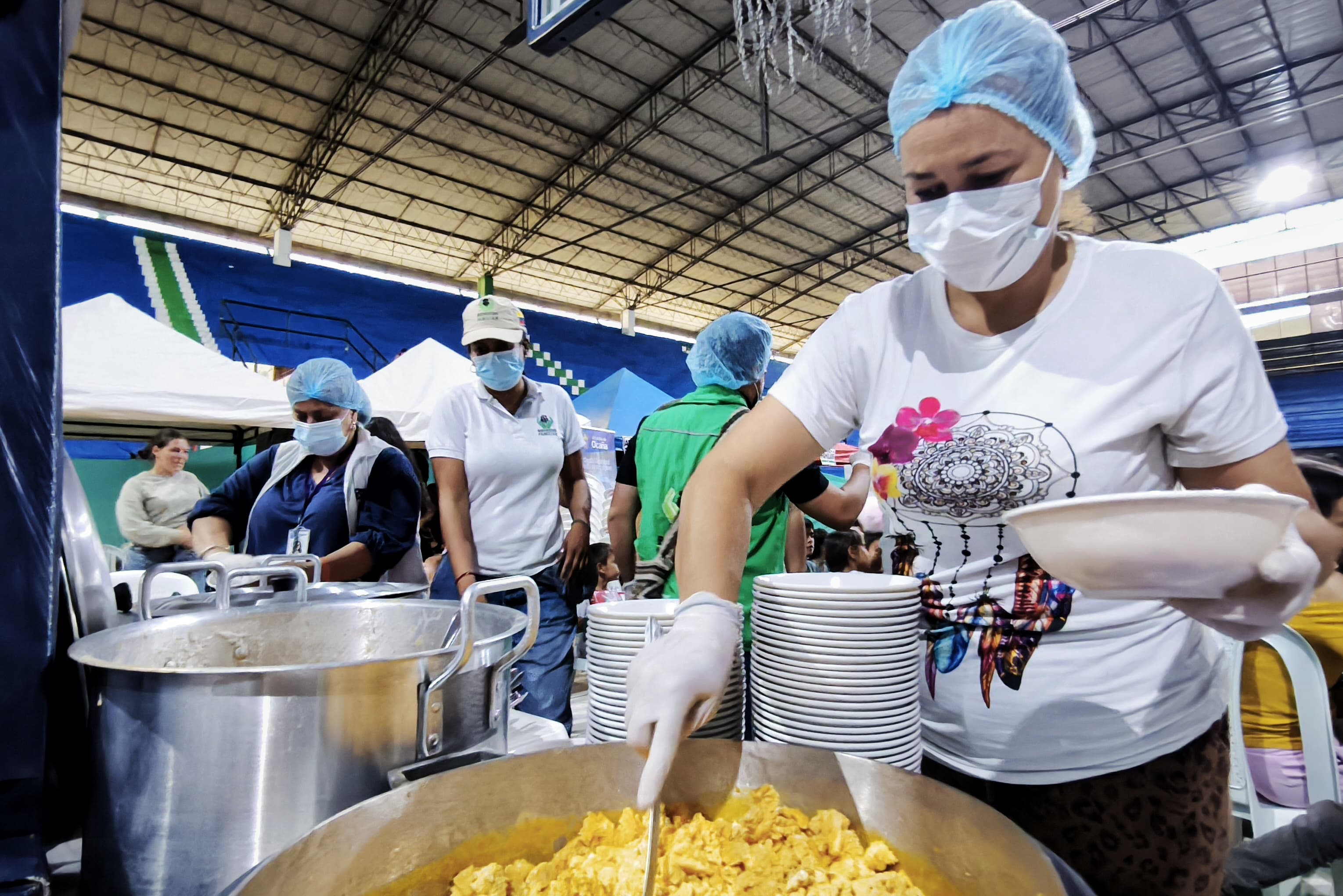 Mujeres con cofia y tapabocas sirven de grandes ollas con comida alimentos calientes en comedor comunitario de Cartagena, Bolívar