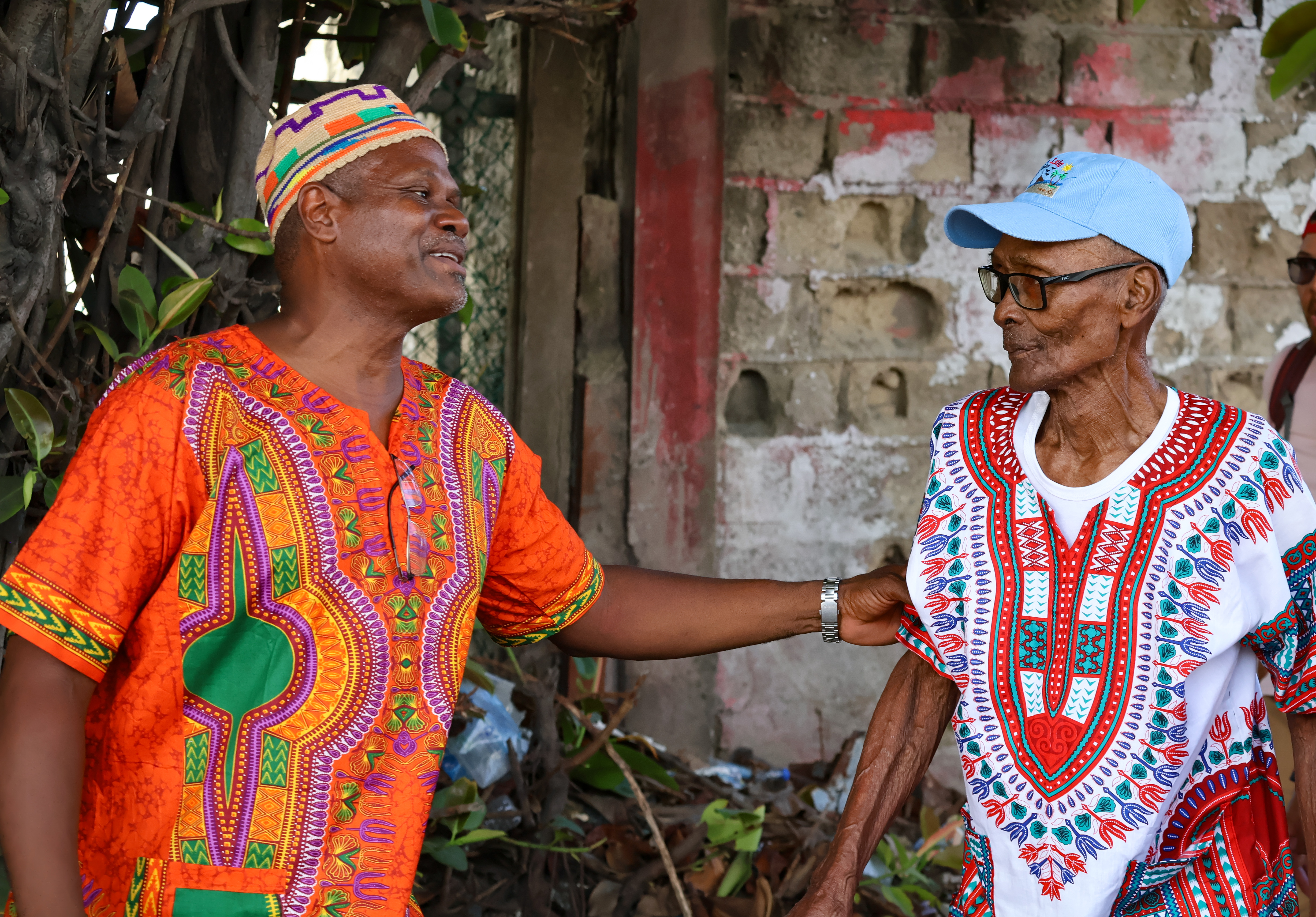 Hombres raizales mayores vestidos con coloridad prendas se saludan afectuosamente en  una calle de la isla de San Andrés