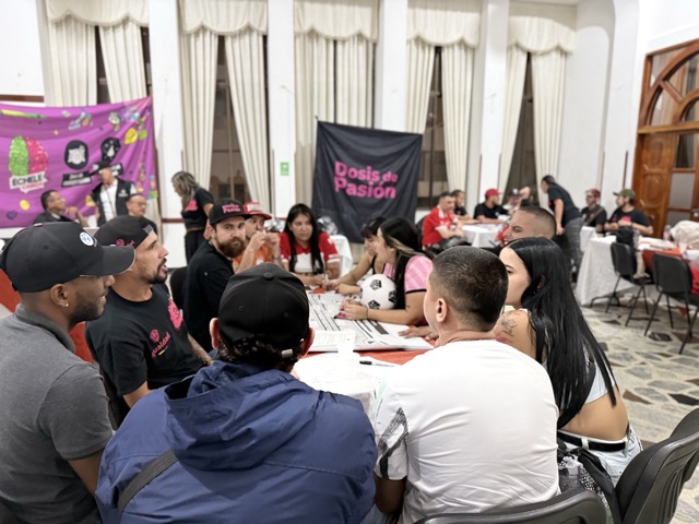 Grupo de personas sentadas alrededor de una mesa, participando en un taller sobre autocuidado y prevención de riesgos.