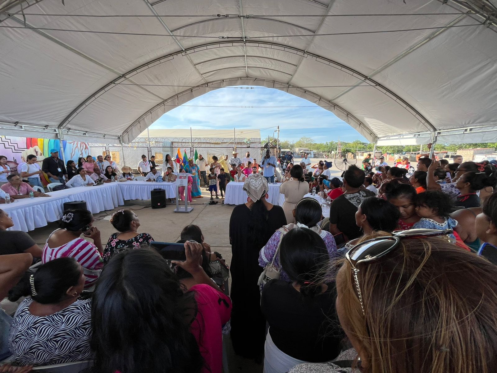 Plano general de una carpa gigante donde habitantes de La Pista escuchan la oficializacion de ese territorio como Barrio de Paz de Maicao, en La Guajira