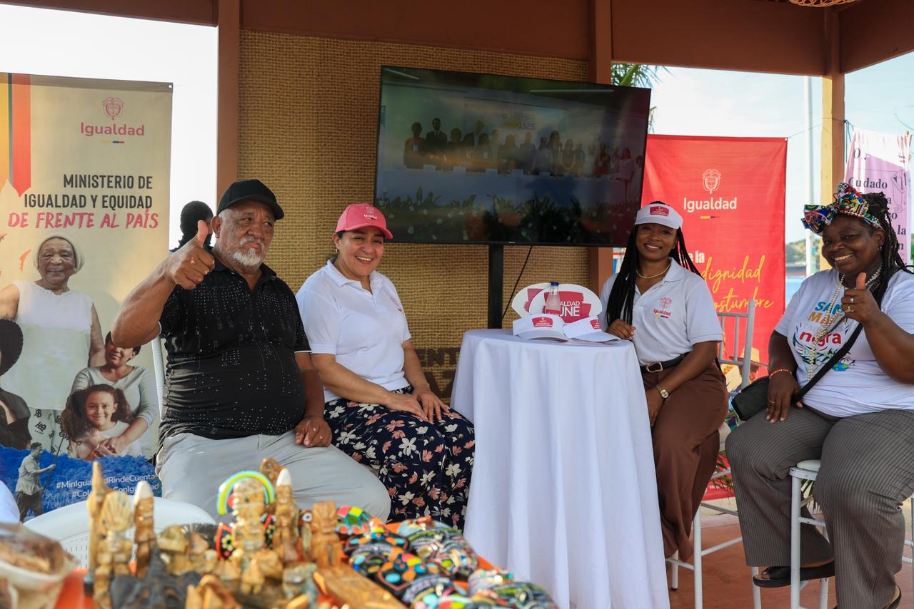 Grupo de emprendedores de personas mayores sentados con sus artesanías en el stand de minigualdad en Santa Marta