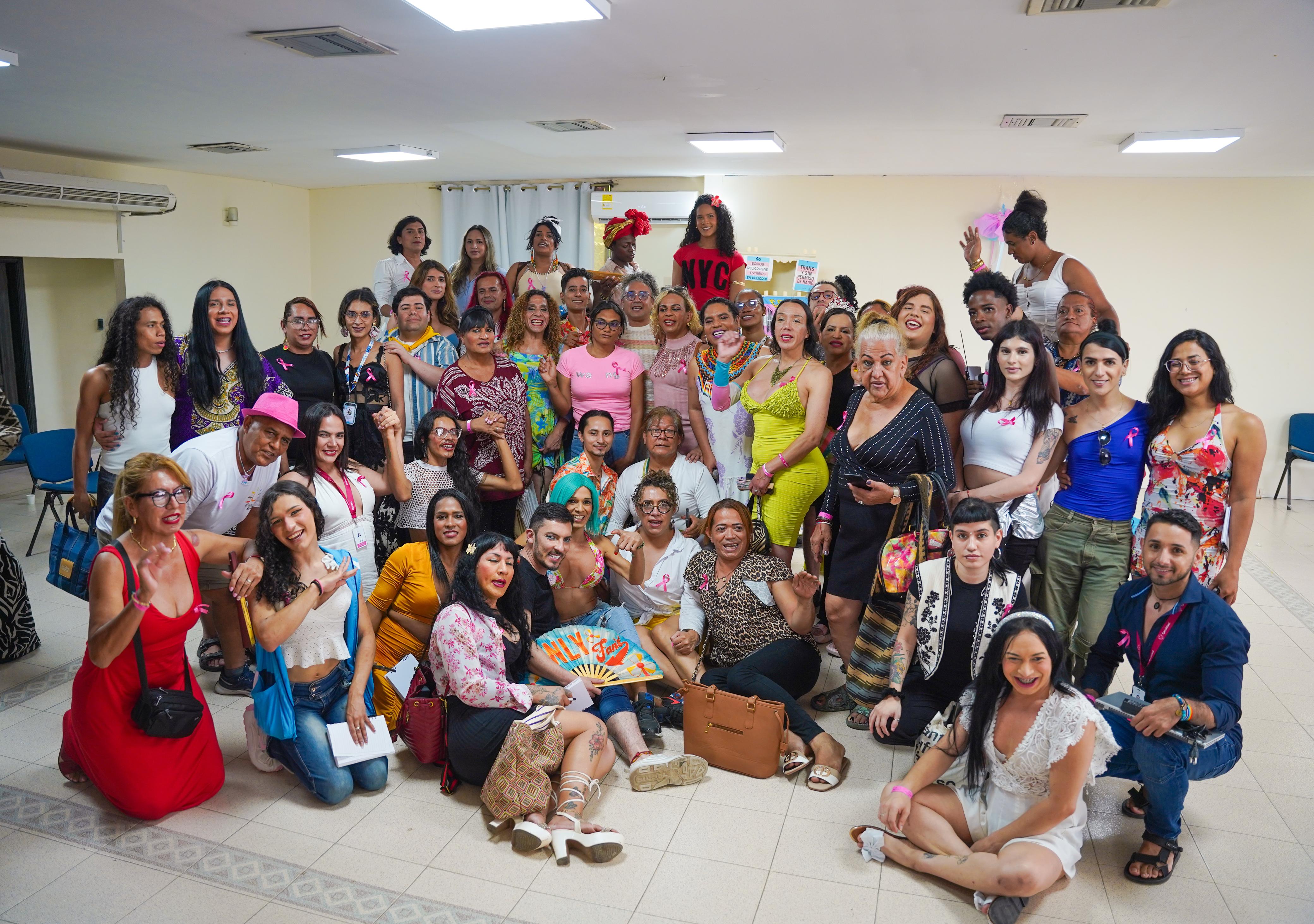 Ministro Juan Florián sentado en el piso acompañado de un nutriodo grupo de lideresas tranfemeninas